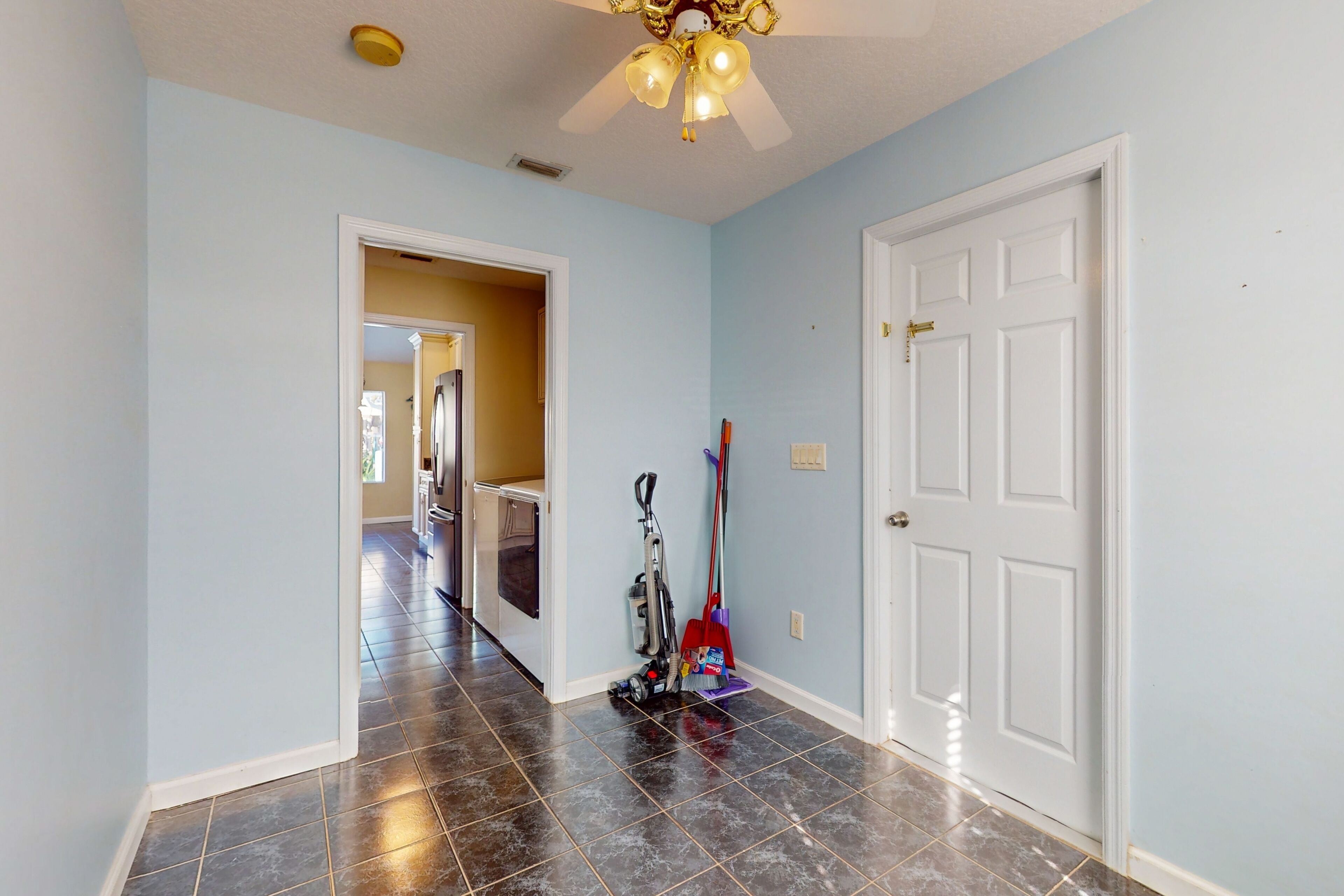 A hallway with a ceiling fan, a white door, and a vacuum cleaner.