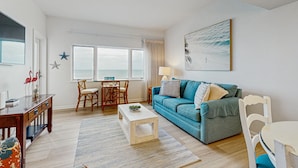 Una sala de estar con un sofá azul, una mesa de centro de madera y un comedor con mesa y sillas.