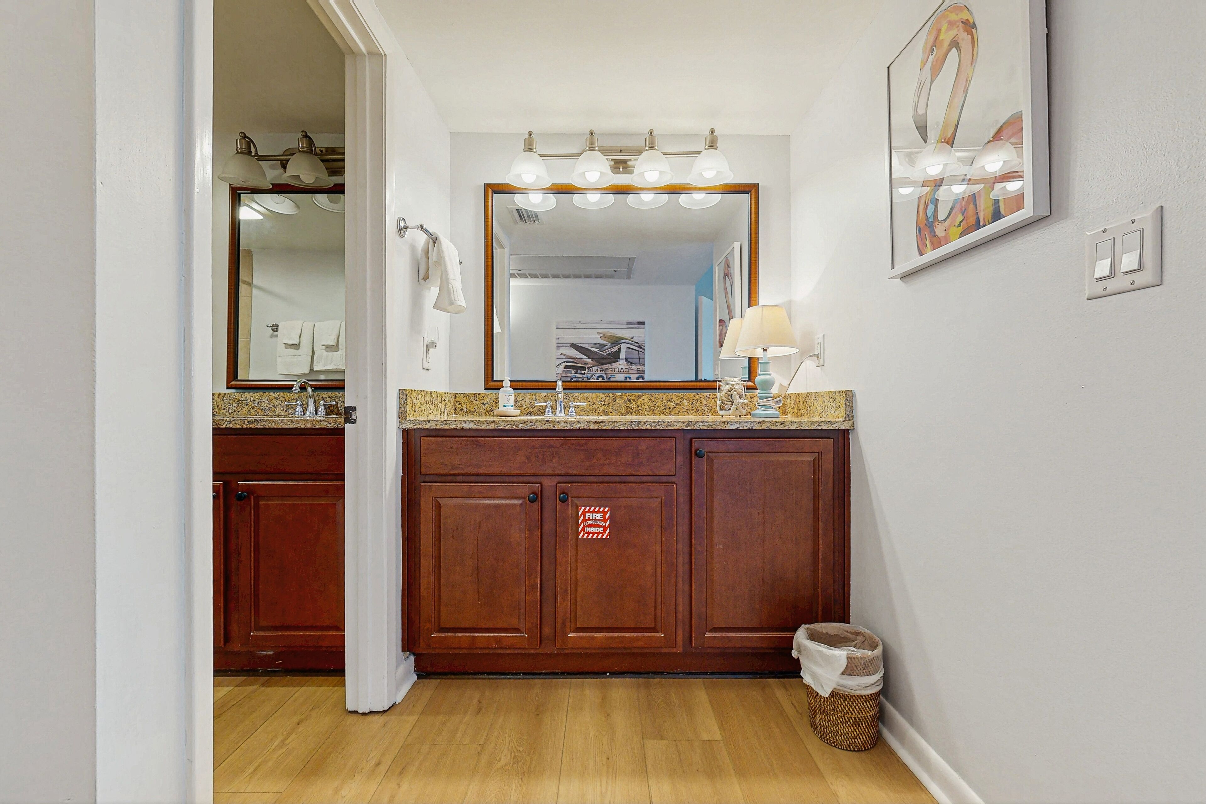 A bathroom with a wooden vanity, a large mirror, and a lighted vanity area.