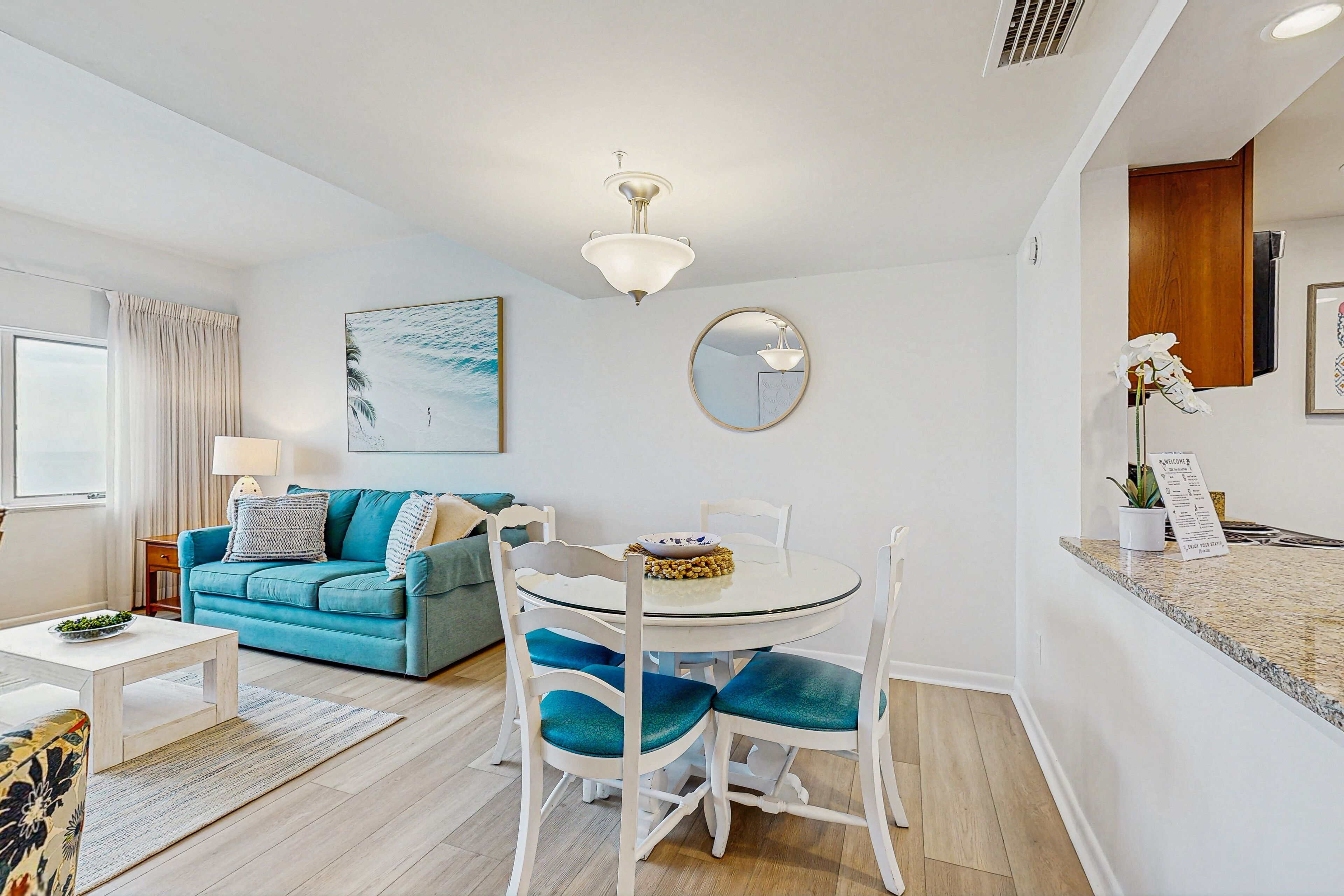 A modern living room with a blue sofa, white dining table, and chairs.