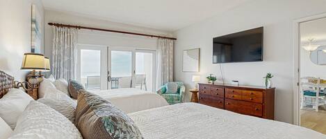 A hotel room with two beds, a TV, a wooden dresser, and a view of the outdoors.