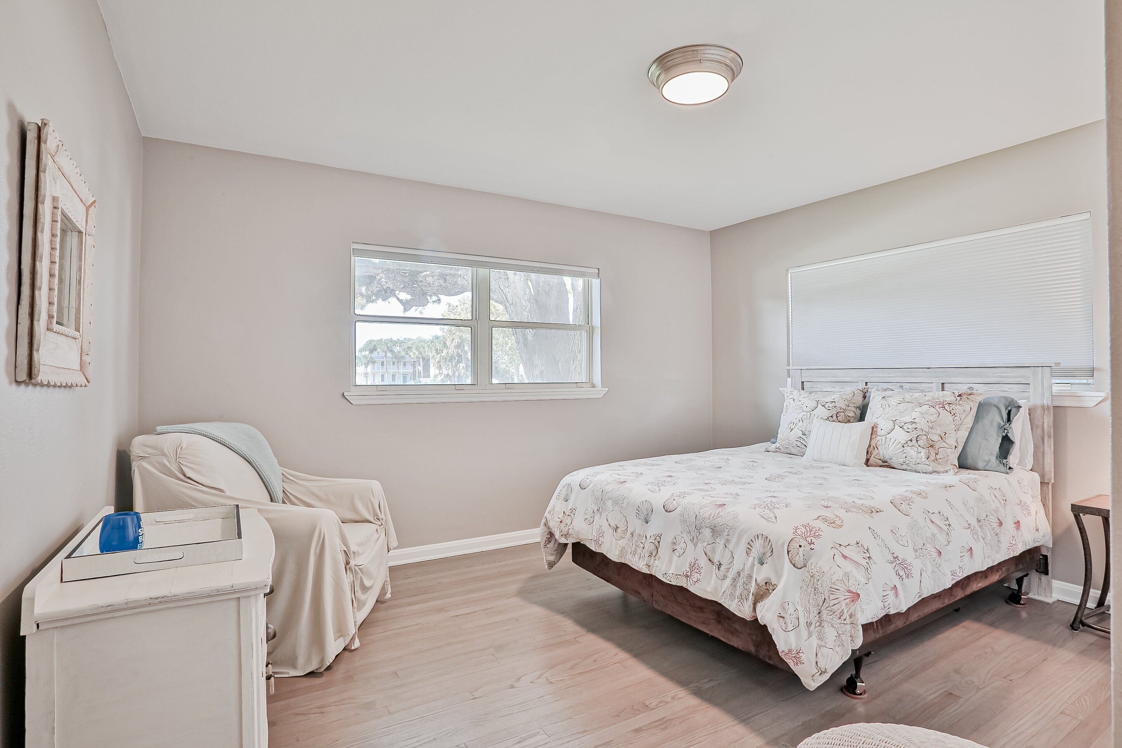 A bedroom with a bed, a chair, a window, and a ceiling light.