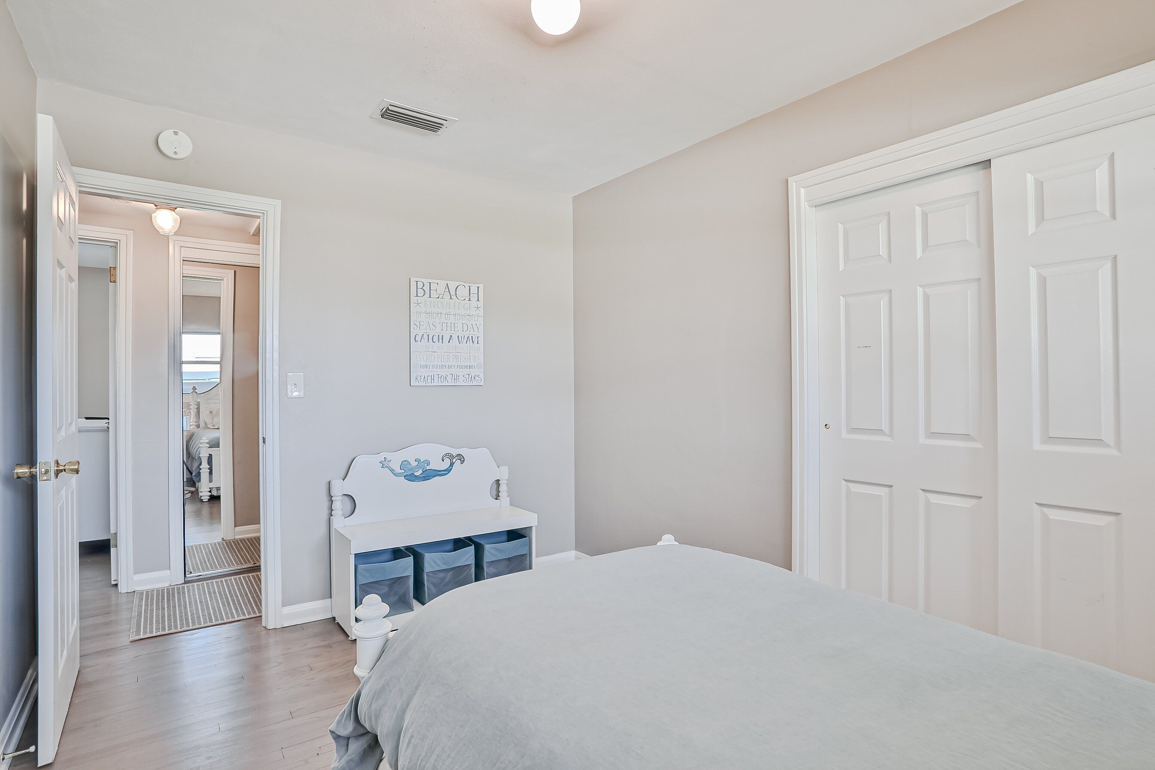 Un dormitorio con cama, cómoda, espejo y puerta.
