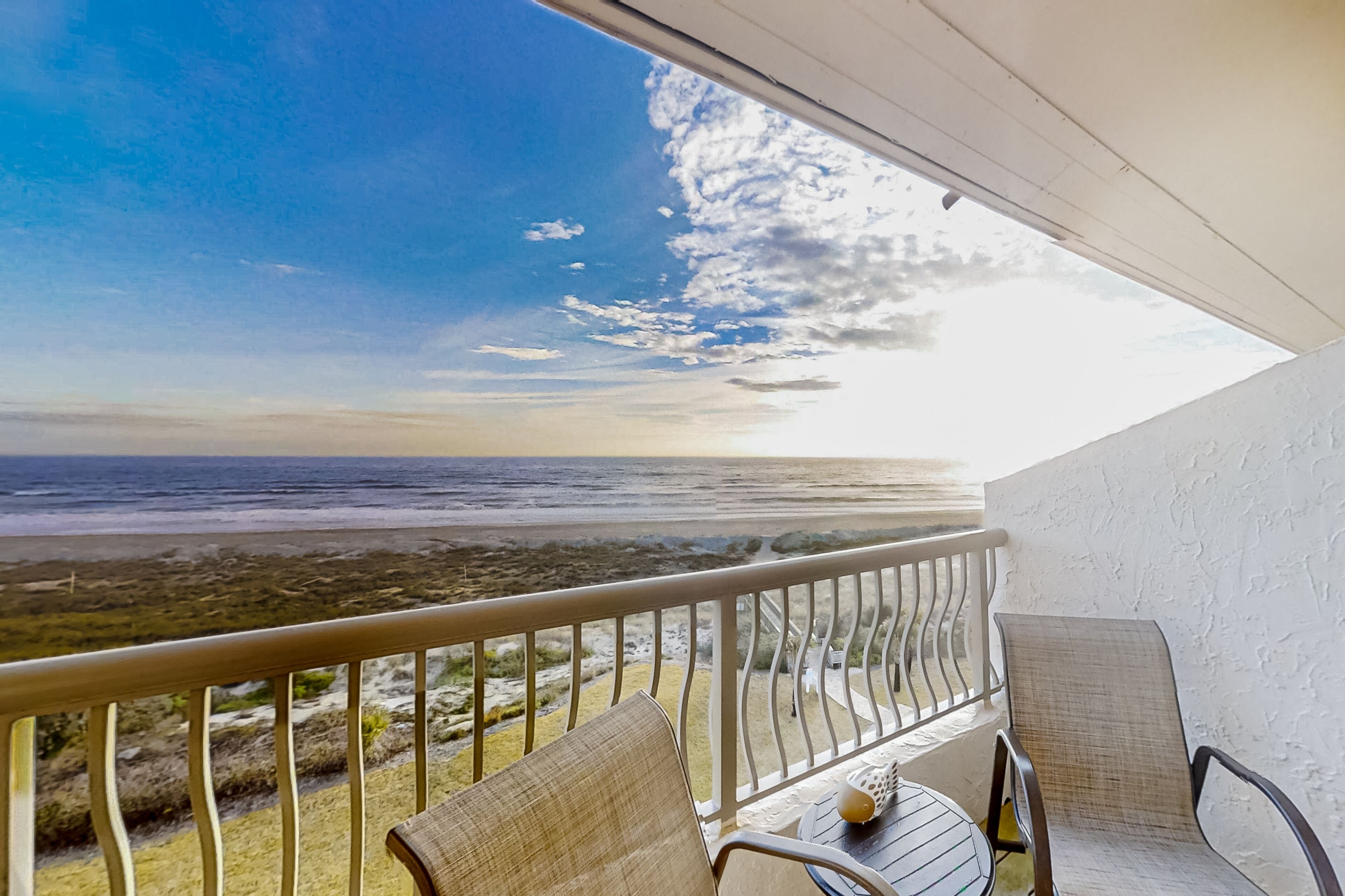 A balcony with a view of the beach and ocean.