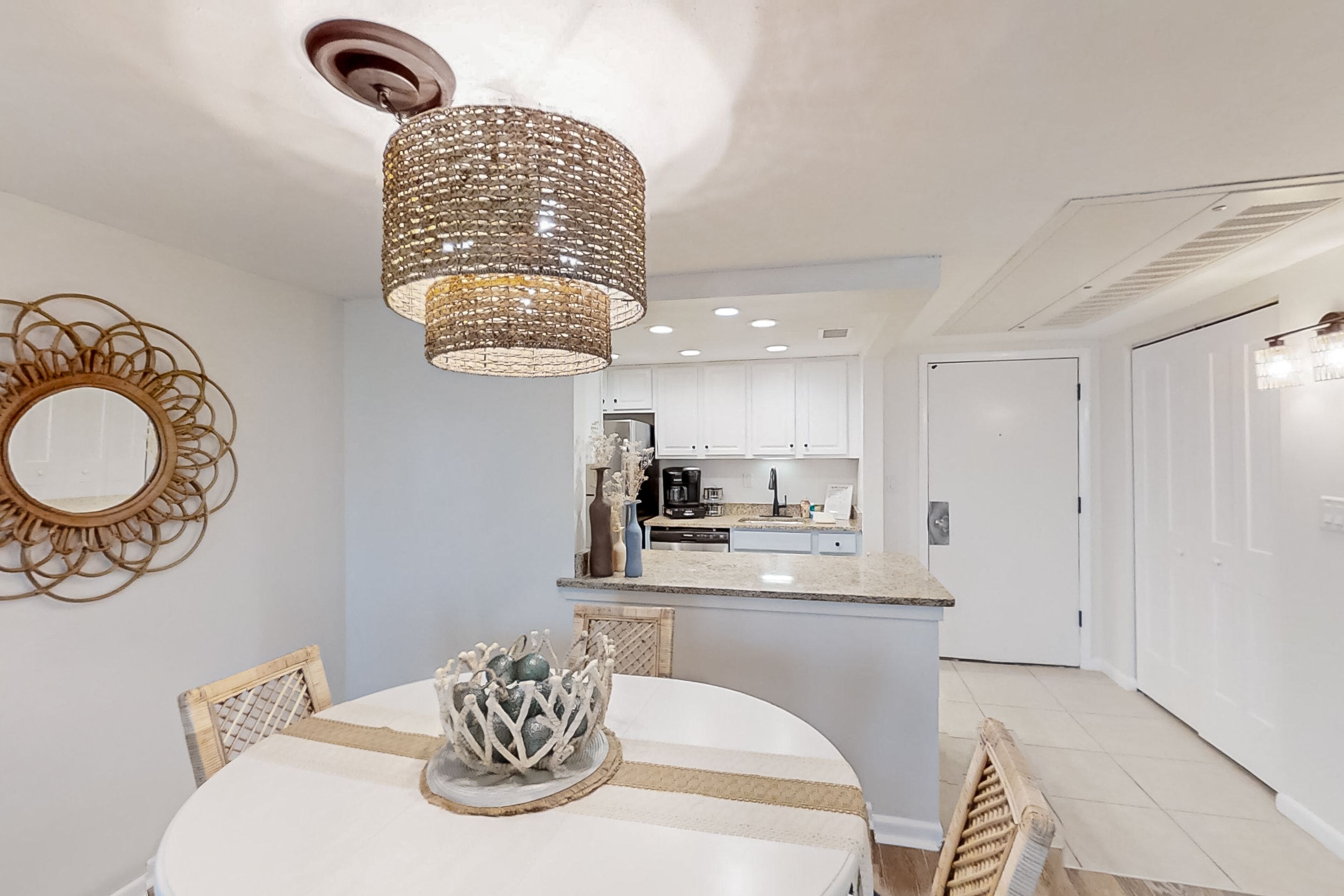 A dining area with a round table, chairs, a decorative centerpiece, and a hanging light fixture.