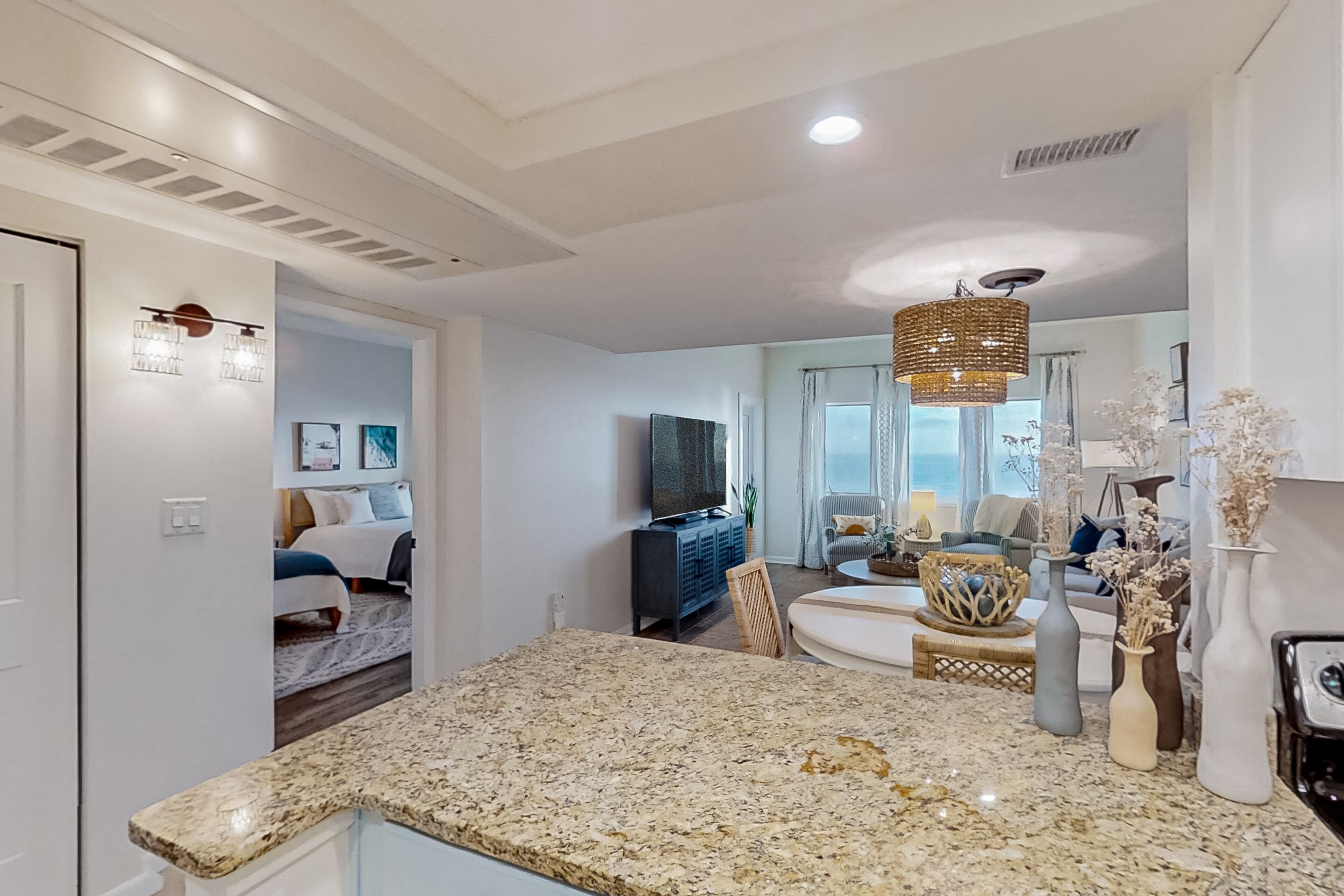 A modern kitchen with granite countertops, a dining area with a round table, and a living room with a TV and comfortable seating.