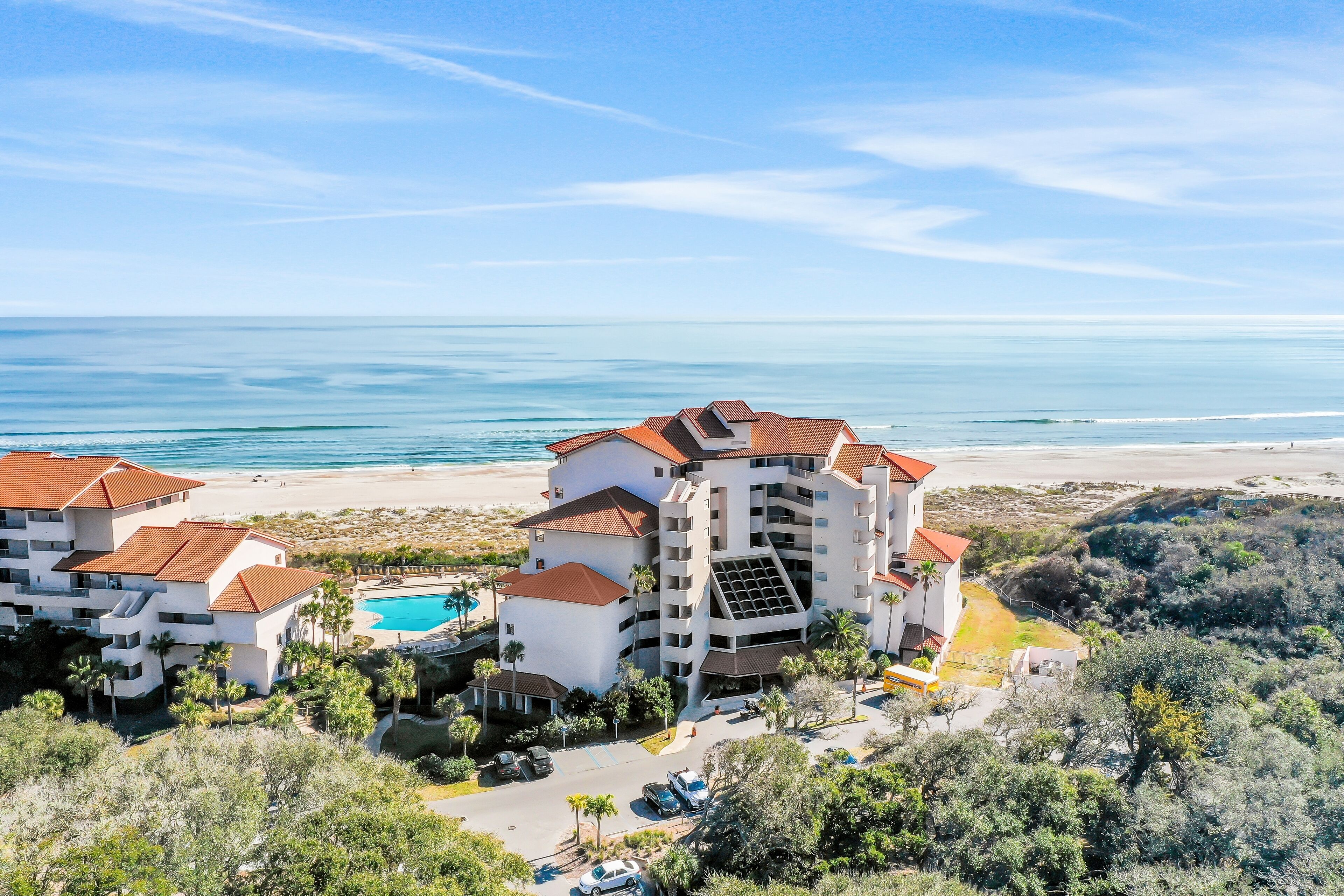 A coastal hotel with multiple buildings, a swimming pool, and a view of the beach and ocean.