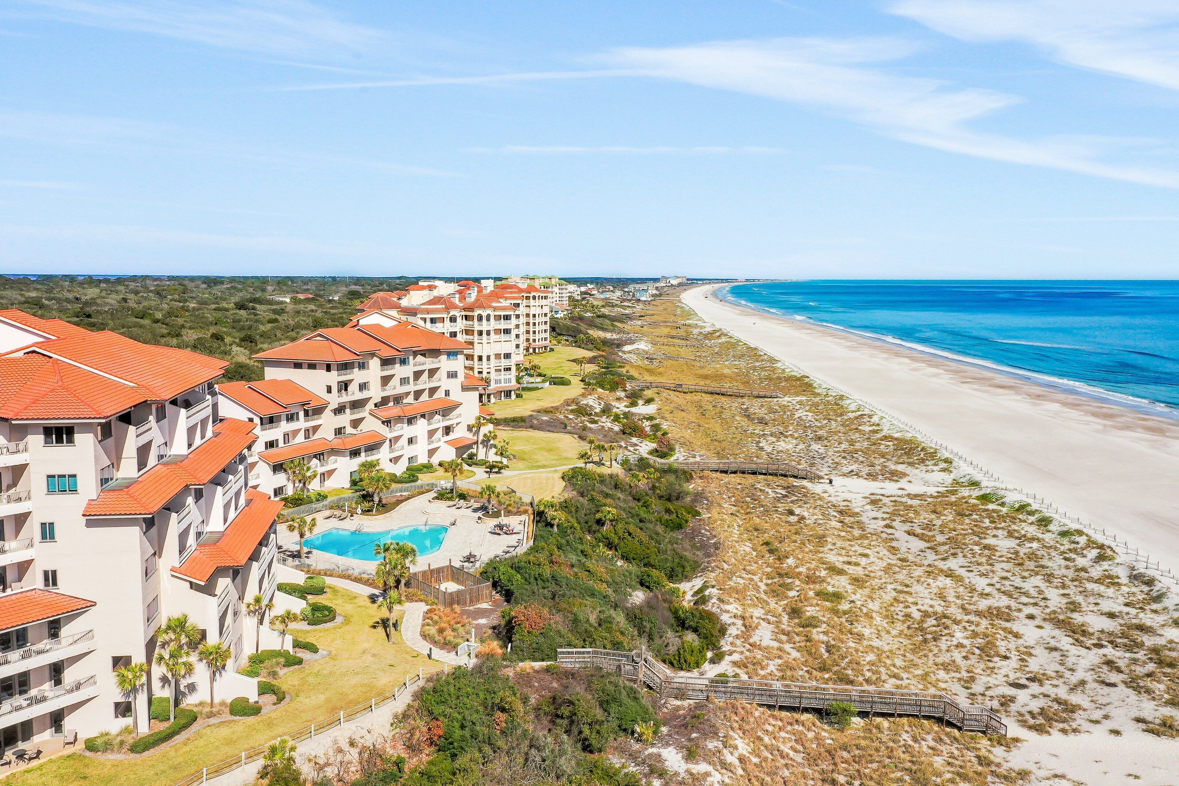 A beachfront hotel with multiple buildings, a swimming pool, and a beach access walkway.