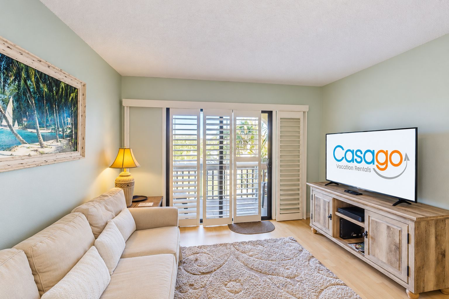 A living room with a sofa, a television, a lamp, and a sliding glass door leading to an outdoor area.