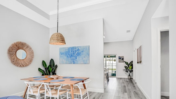Un comedor moderno con una mesa de madera, sillas blancas y una lámpara colgante en cesto.