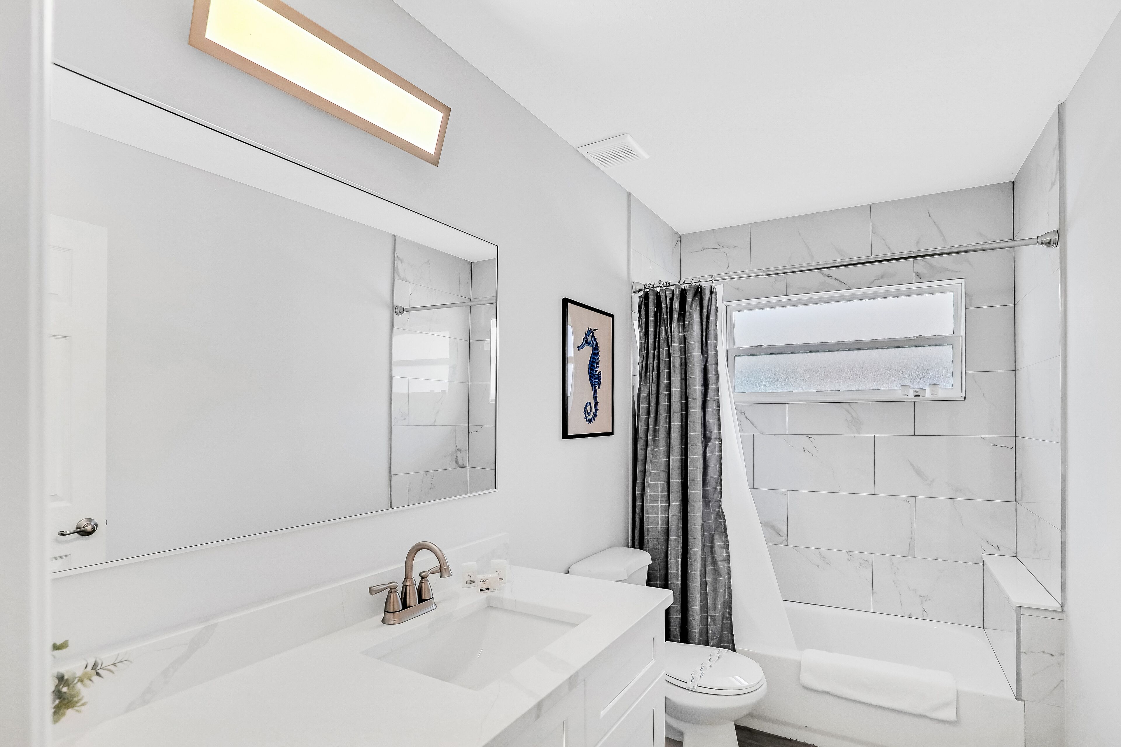 A modern bathroom with a large mirror, a sink, and a toilet.