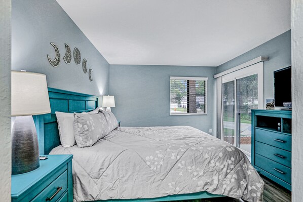 A bedroom with a bed, nightstands, a dresser, and a window with a view. - Charming Home Near Beach & Golf With Central AC & Patio - Dog-friendly (Palm Coast)