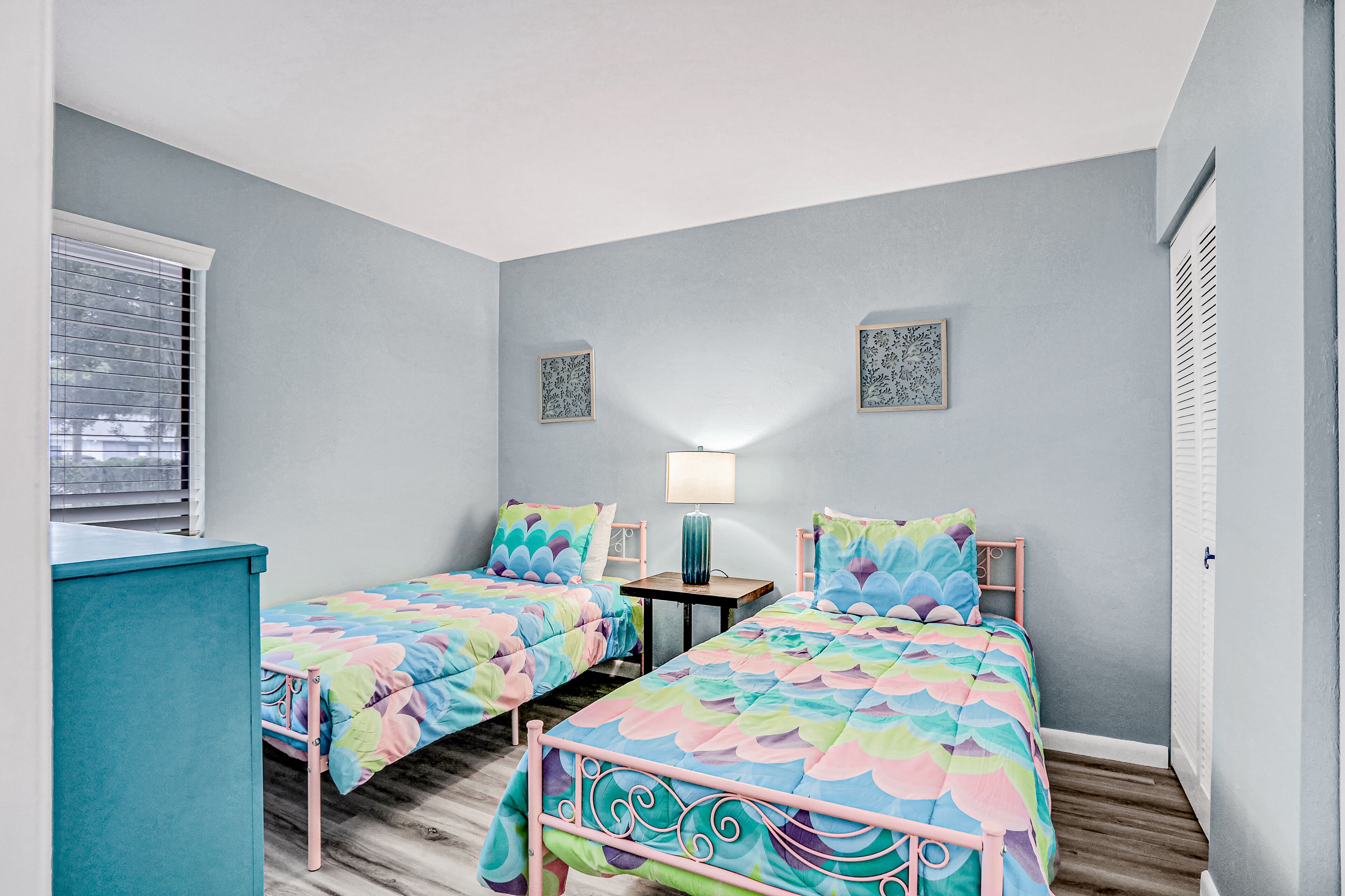 A bedroom with two single beds, a small table, and a lamp.