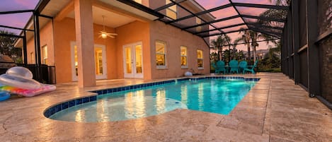 A swimming pool with a covered patio area, a ceiling fan, and a view of a house.