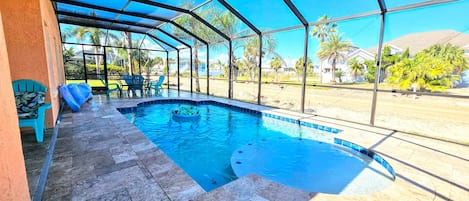 A covered swimming pool with a tiled floor, surrounded by a metal frame and glass panels.