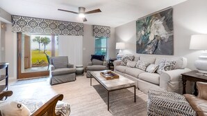Ein geräumiges Wohnzimmer mit einer großen Couch, zwei Sesseln, einem Couchtisch und einem Deckenventilator.