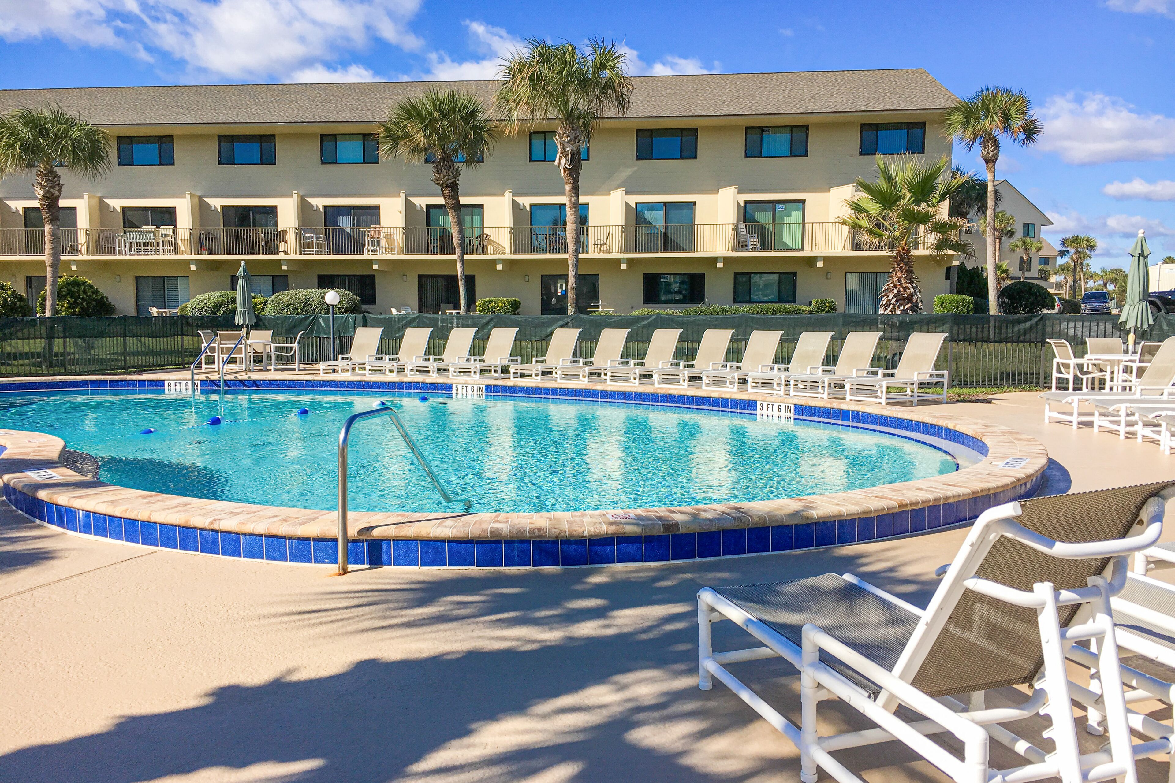 A swimming pool with lounge chairs and a building in the background.