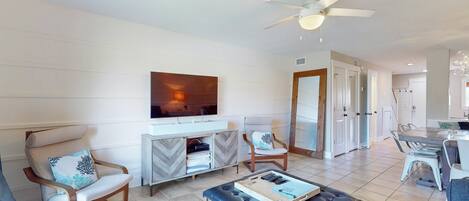 Una sala de estar moderna con sofá, sillones, una mesa de centro y televisión.