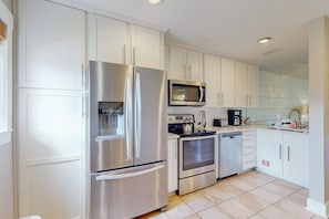 A modern kitchen with stainless steel appliances, white cabinetry, and a tiled floor. - A1A South St Augustine 2 Bedroom Oceanview Condo Sleeps 8 (St. Augustine)