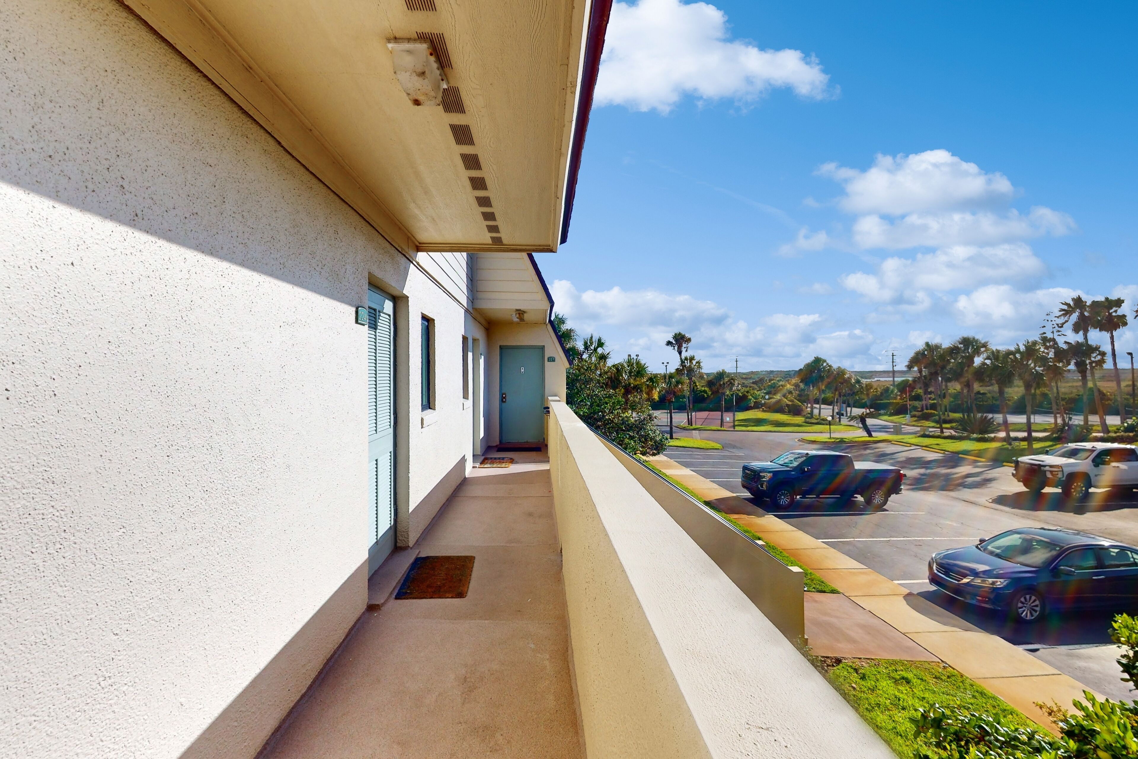 A hotel corridor with a view of a parking lot and palm trees.