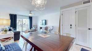 A spacious living area with a wooden dining table, a ceiling fan, and a modern chandelier. - A1A South St Augustine 2 Bedroom Oceanview Condo Sleeps 8 (St. Augustine)