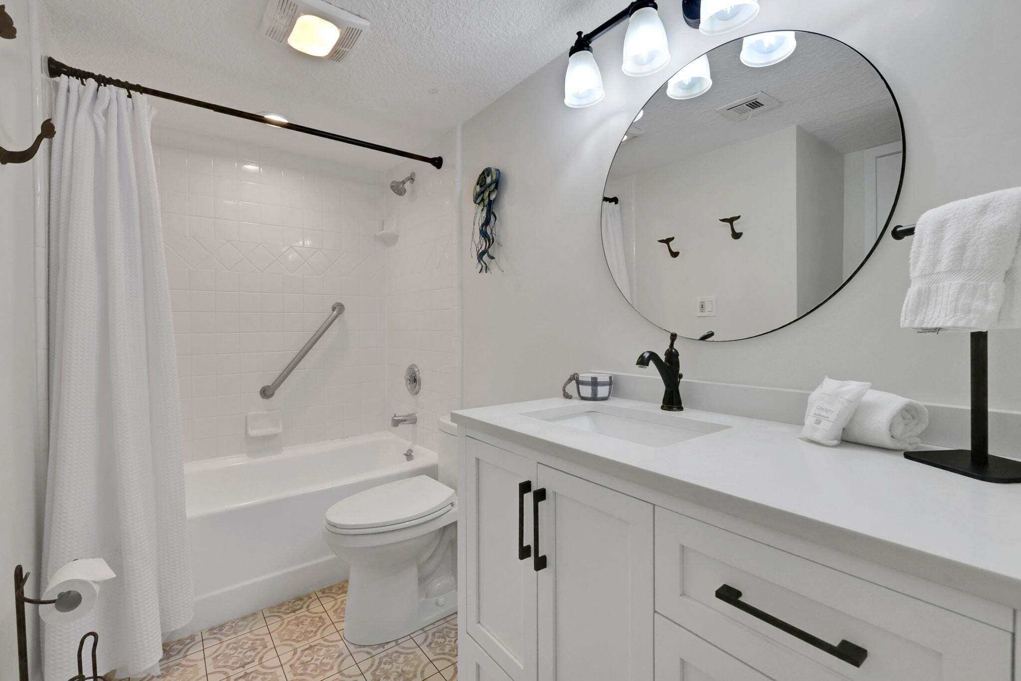 Un baño moderno con bañera, inodoro, lavabo y un espejo grande.