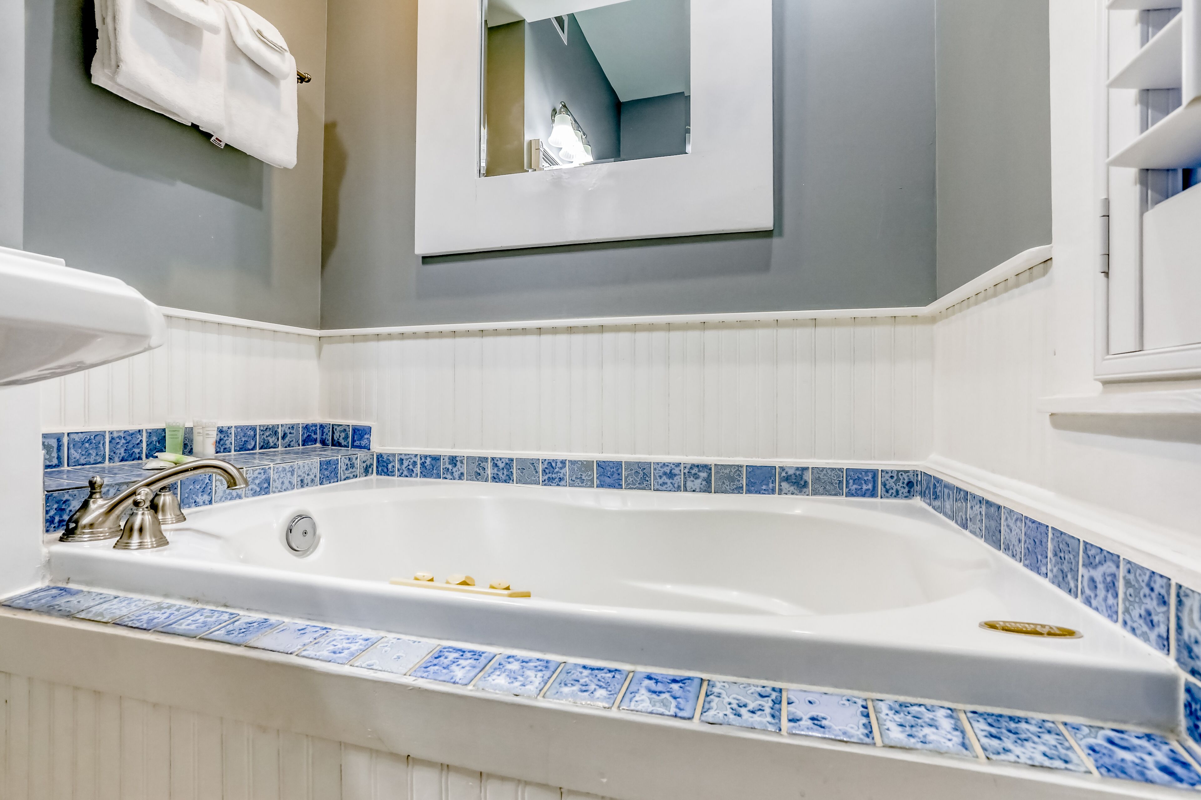 Een badkamer met een groot bad, witte tegels en een blauwe tegelrand.