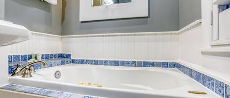Een badkamer met een groot bad, witte tegels en een blauwe tegelrand.