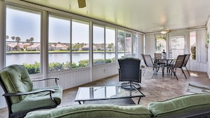 A sunroom with large windows, a ceiling fan, and a dining area with chairs and a table. - Charming Home With Pool, Patio, Tennis, Central AC, & Washer/dryer (St. Augustine)
