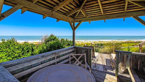 Une terrasse en bois offrant une vue sur la plage et l’océan.