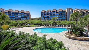 Un hôtel doté d’une piscine entourée de palmiers et de chaises longues.