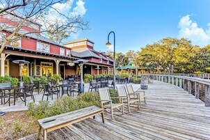 A wooden deck with outdoor seating and a building with a red facade.
