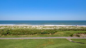 A coastal landscape with a grassy area, a paved path, and the ocean in the background. - Beach Condo With Balcony, W/d, AC, Outdoor Pool & Fast Wifi (Fernandina Beach)