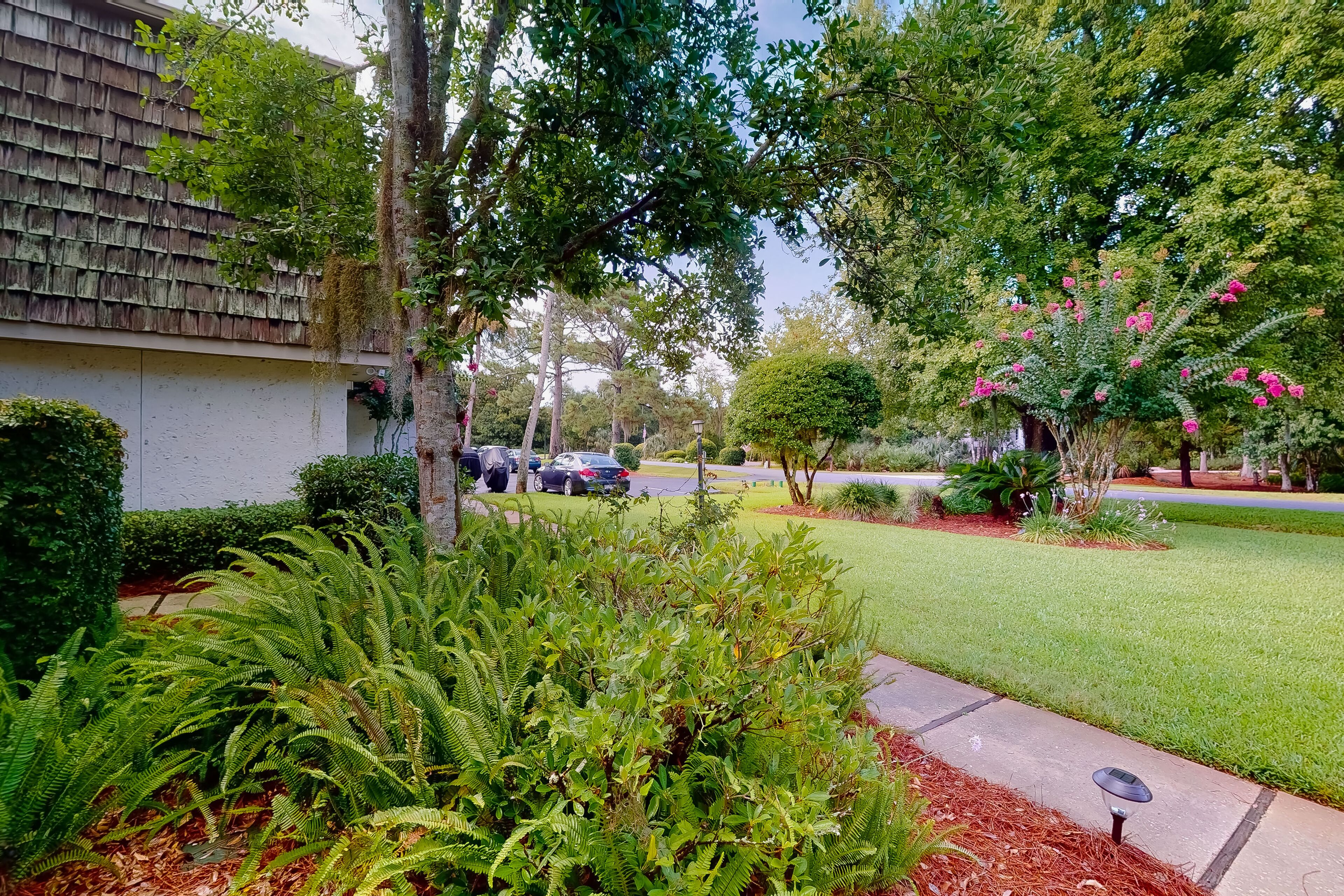 Un quartier résidentiel doté d’une pelouse bien entretenue, de diverses espèces d’arbustes et d’un éclairage extérieur alimenté par énergie solaire.