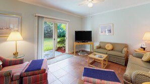 A living room with a television, two sofas, a coffee table, and a ceiling fan. - Condo With Central AC, Washer/dryer, Shared Outdoor Pool, & On-site Golf (St. Simons Island)