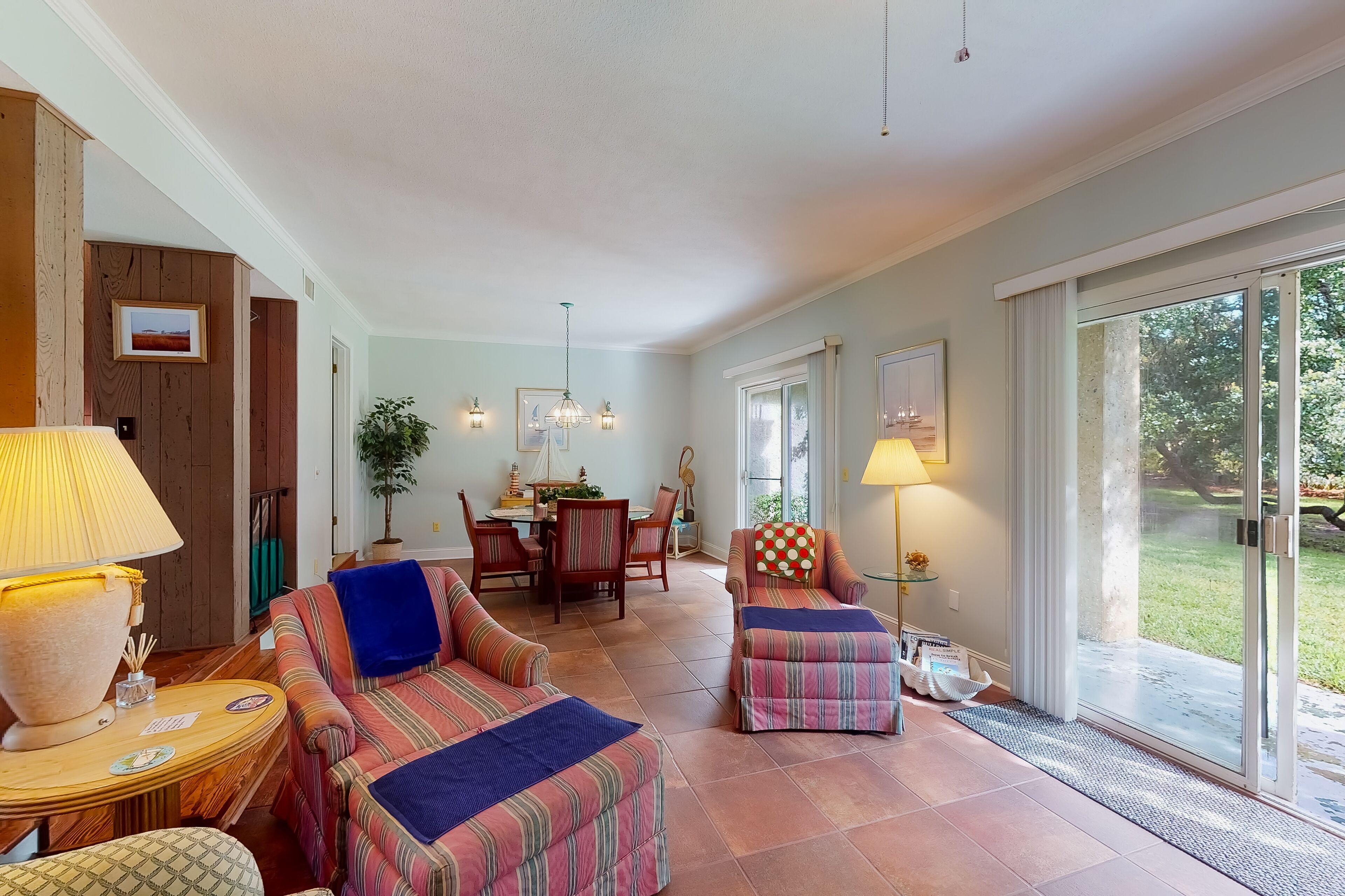A spacious living area with striped sofas, a dining table, and a large sliding glass door to the outdoors.