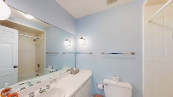 A bathroom with a white sink, two mirrors, a toilet, and a shower.