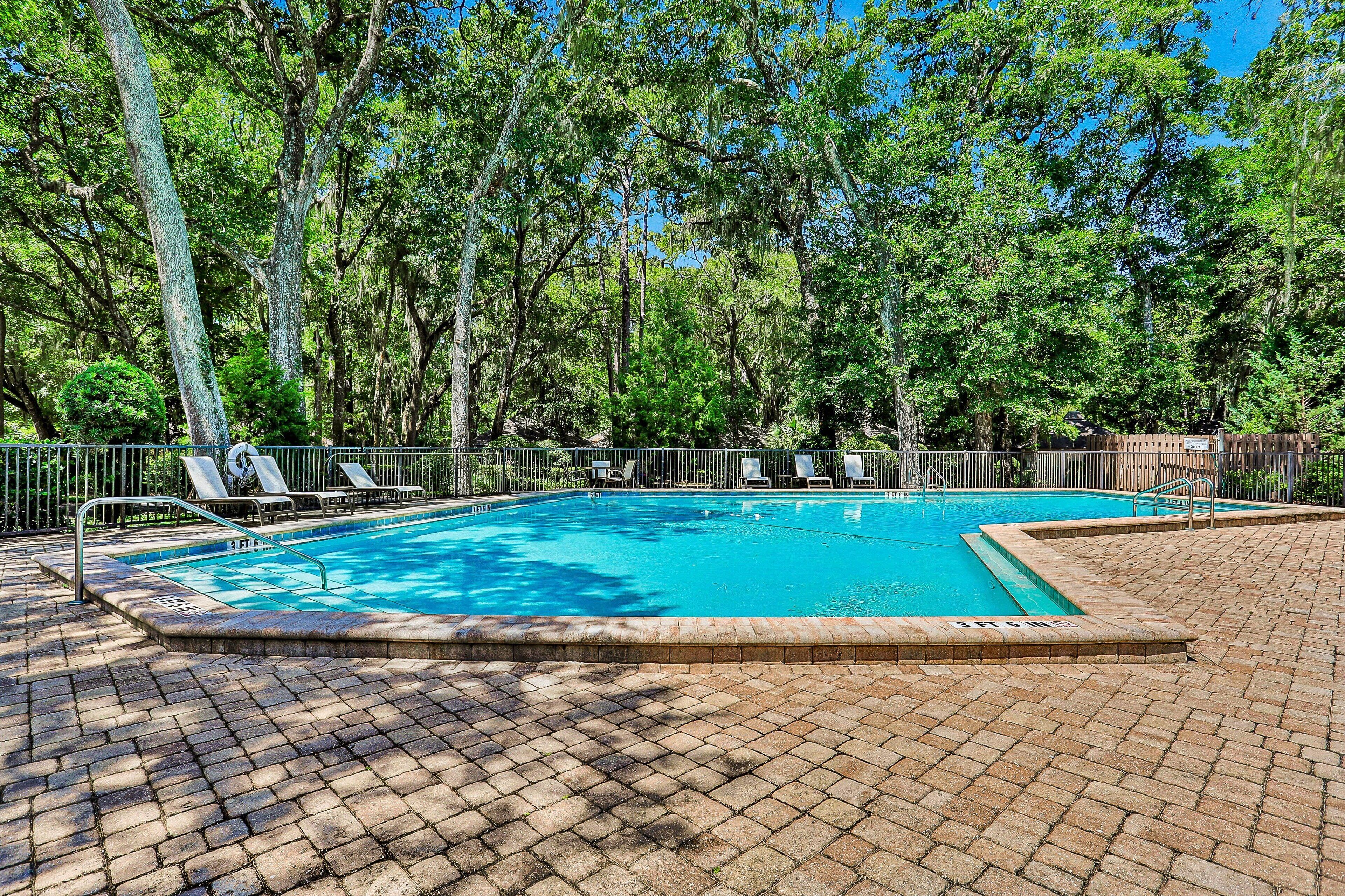 Una piscina rectangular con borde de ladrillo, rodeada por un patio de ladrillo.