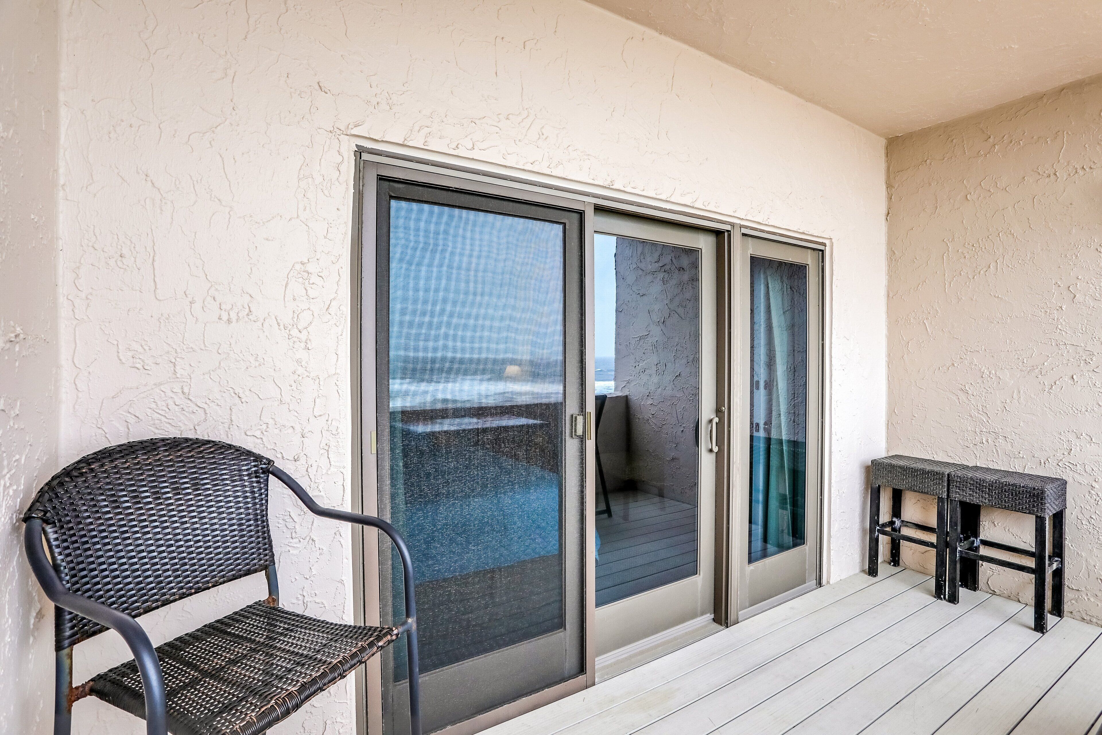 A balcony with a sliding glass door, a wicker chair, and a small table.