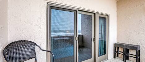 A balcony with a sliding glass door, a wicker chair, and a small table.