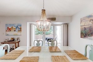 A dining area with a white table, woven placemats, and a chandelier. - 2-story Condo With On-site Pool, Private Patio, & W/D - Near Beach/golf (Fernandina Beach)