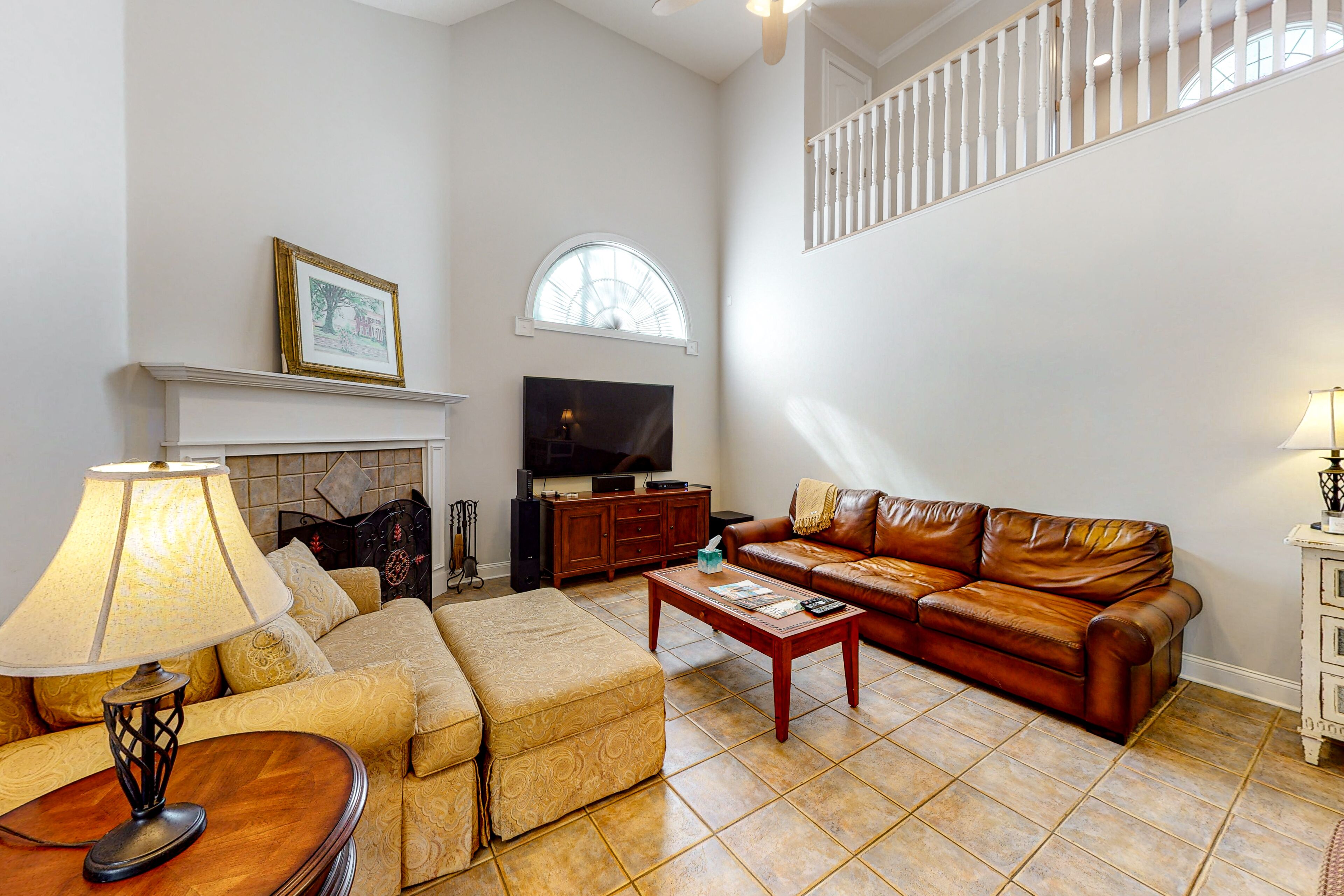 A living room with a fireplace, leather sofa, and a television.