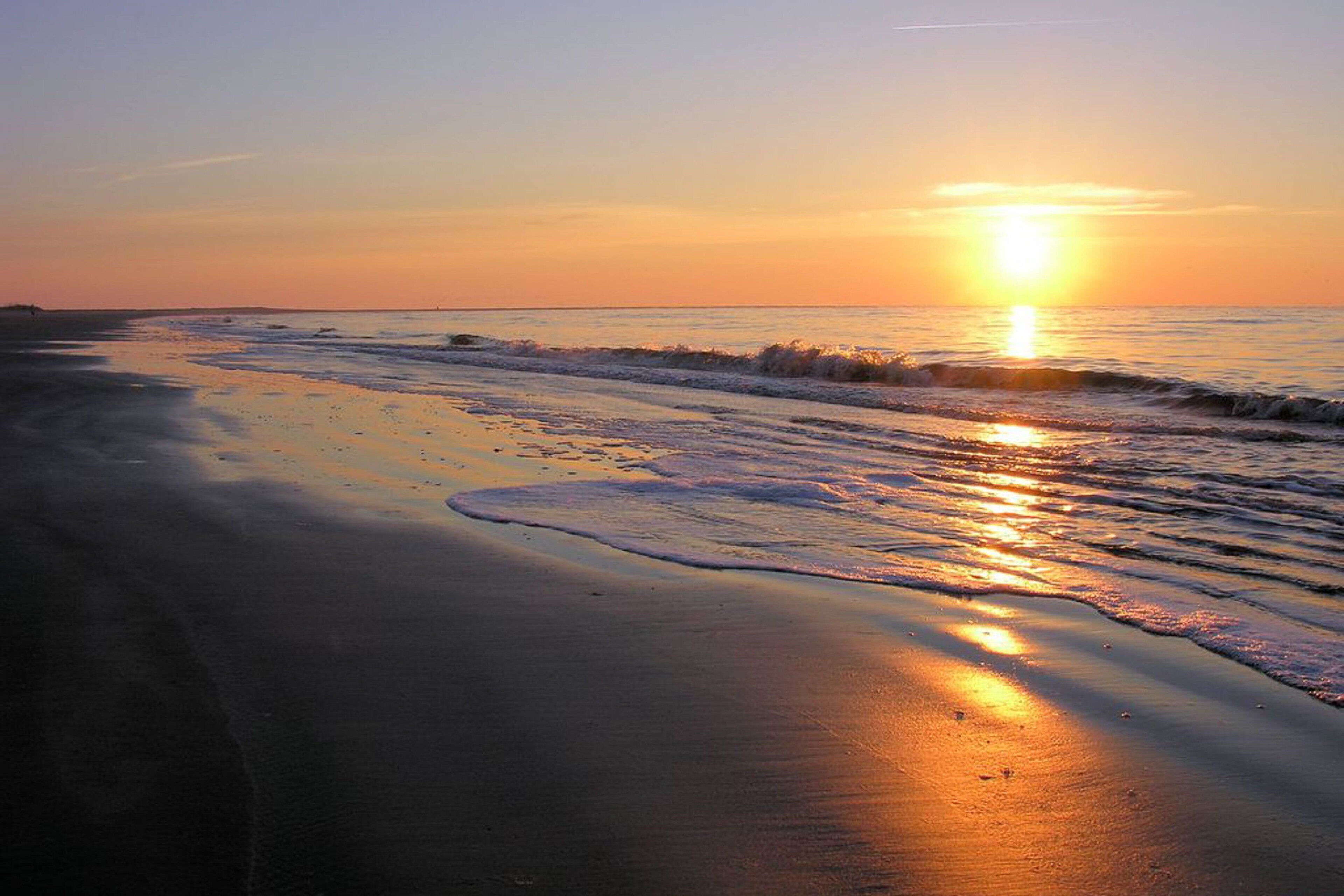 A beach at sunset with waves gently lapping the shore.