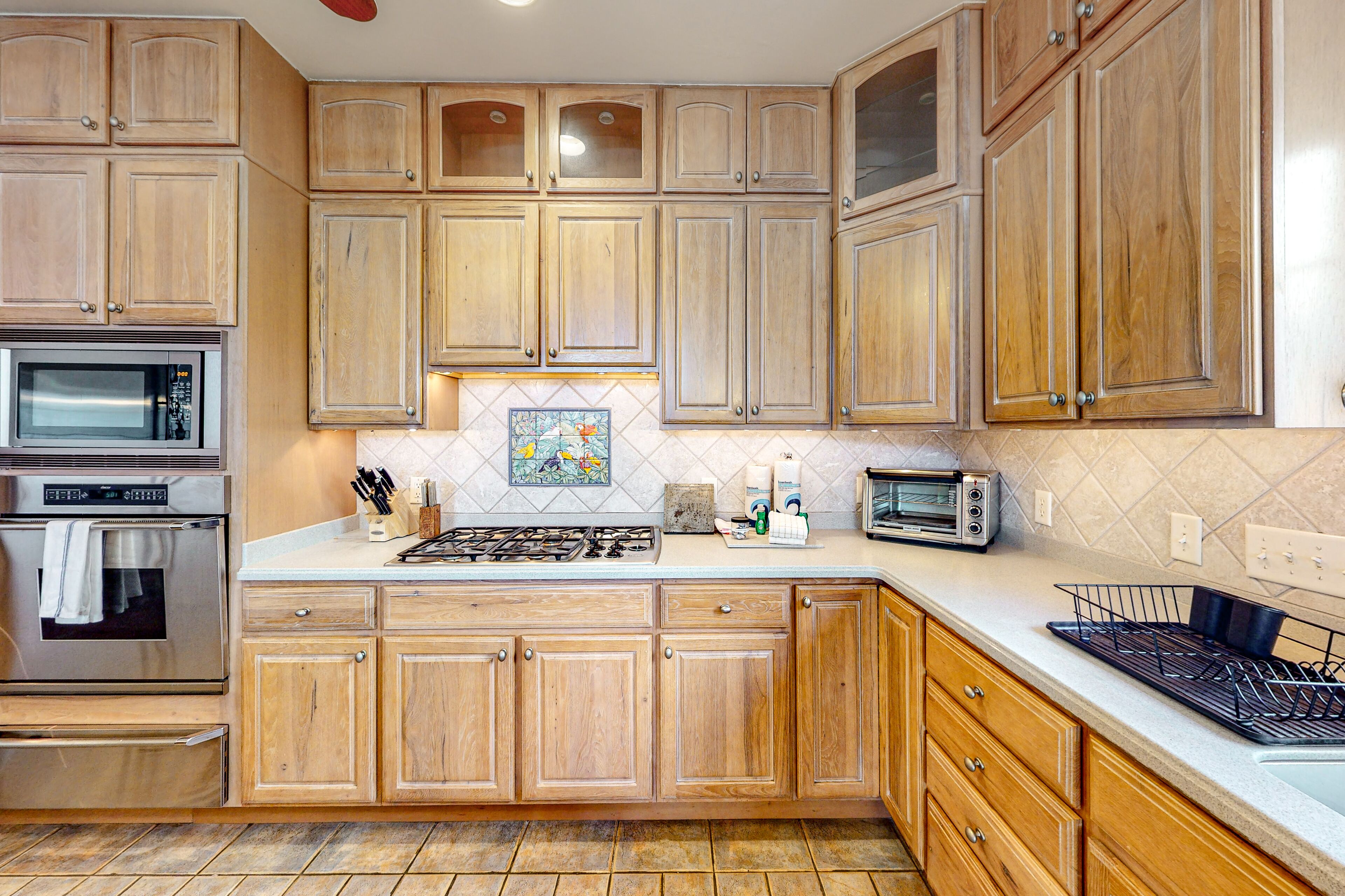 A kitchen with wooden cabinets, a stove, microwave, and a toaster.
