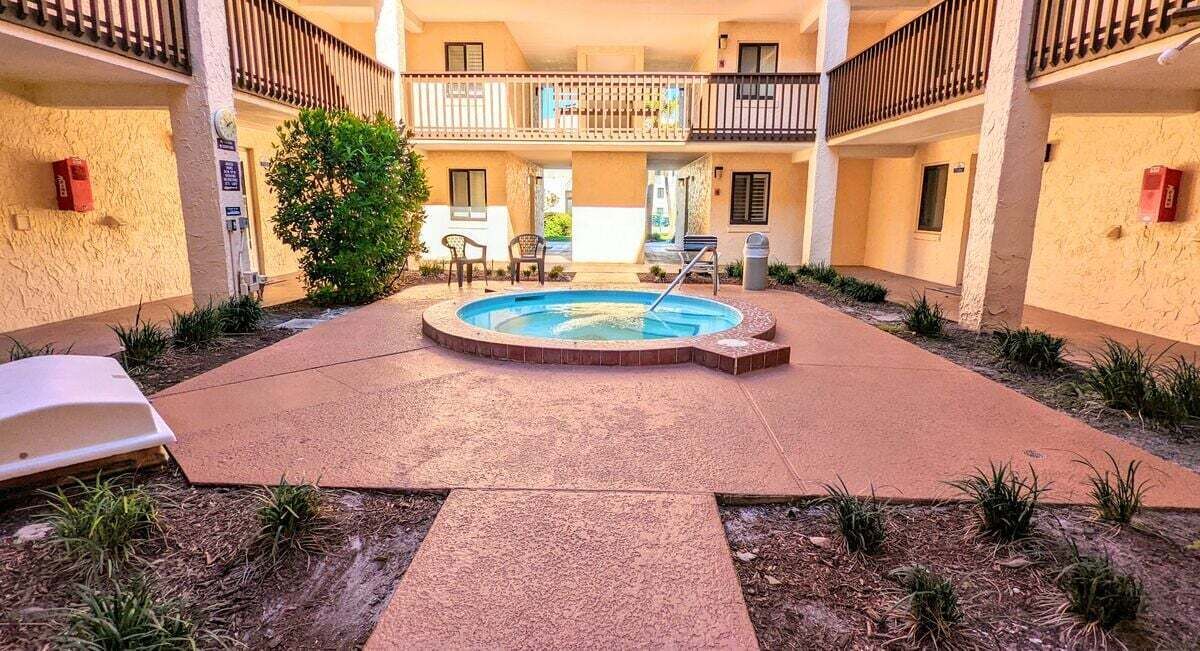 A courtyard with a swimming pool, outdoor seating, and a two-story building with balconies.