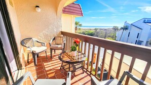 A balcony with two chairs, a small table, and a potted plant. - Casatawaves Ocean View Villa Awesome Resort Pools! Trolley! (St. Augustine)