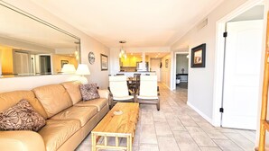 A living room with a sofa, a wooden coffee table, and a dining area with chairs and a table. - Casatawaves Ocean View Villa Awesome Resort Pools! Trolley! (St. Augustine)