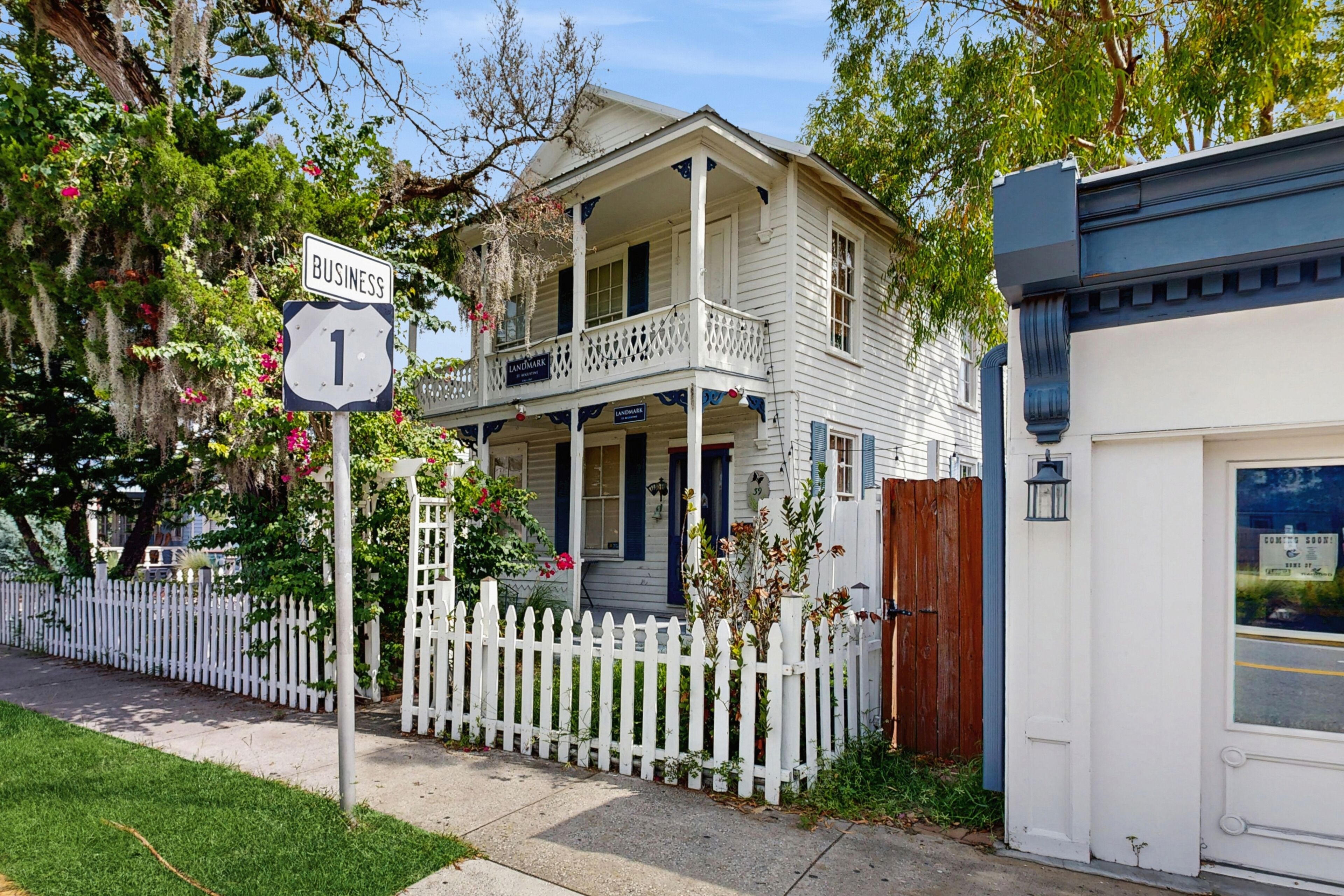 A two-story house with a porch, a white picket fence, and a 'Business 1' sign.