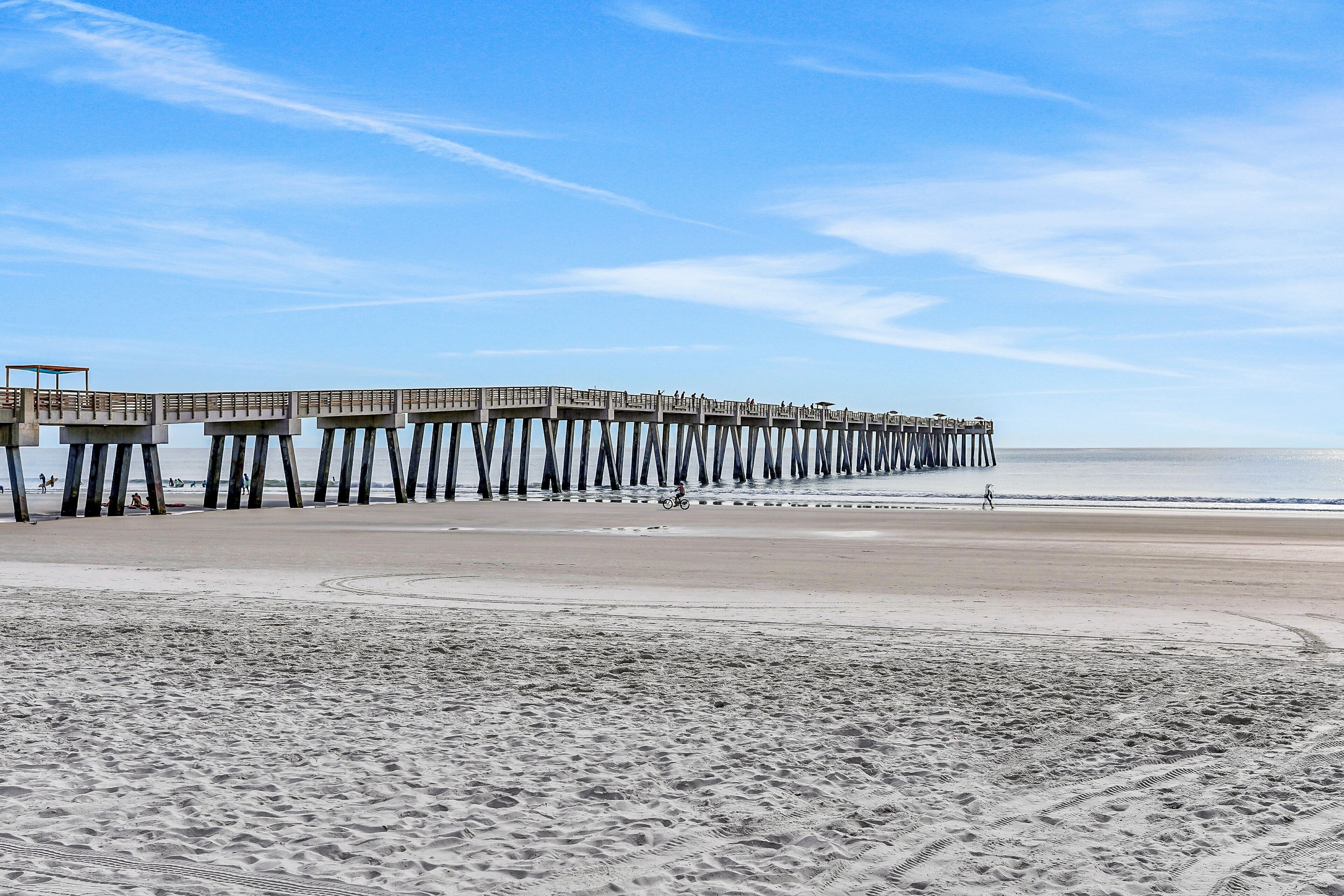 A pier extending into the ocean with a sandy beach in the foreground.