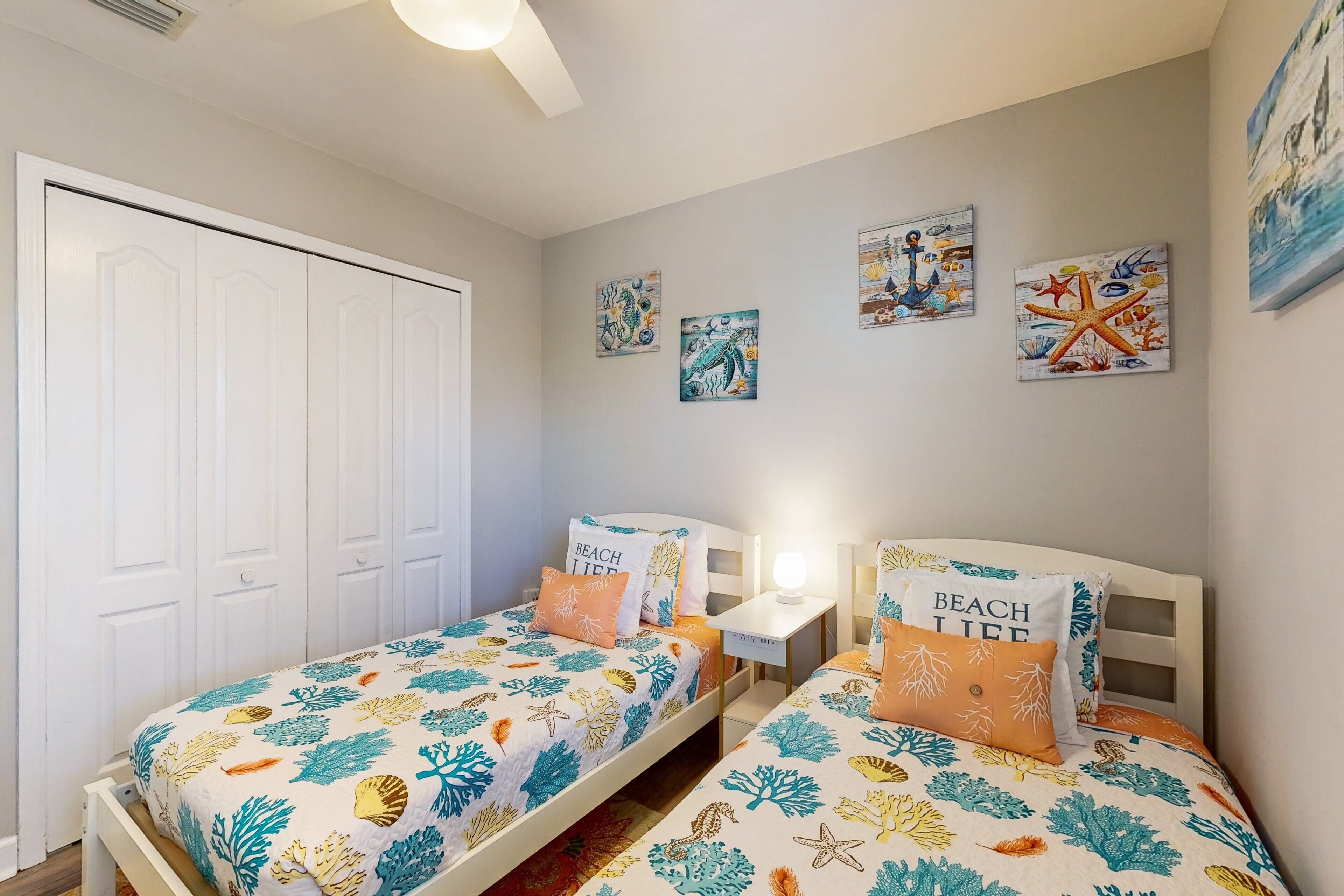 A bedroom with two beds, a nightstand, a desk, and a wardrobe.